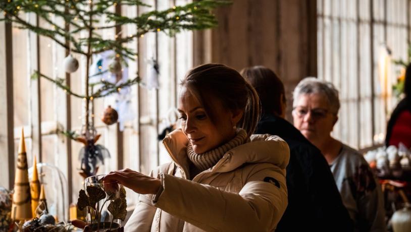 Frau betrachtet Weihnachtsdekorationen auf dem Weihnachtsmarkt der Götter von Tirsbæk