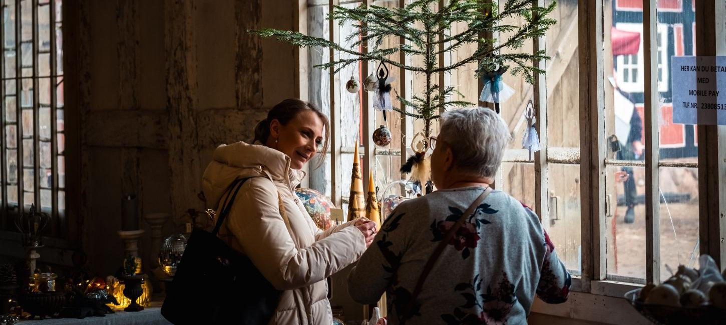 Zwei Personen schauen sich Stände auf dem Weihnachtsmarkt bei Tirsbæk Gods an