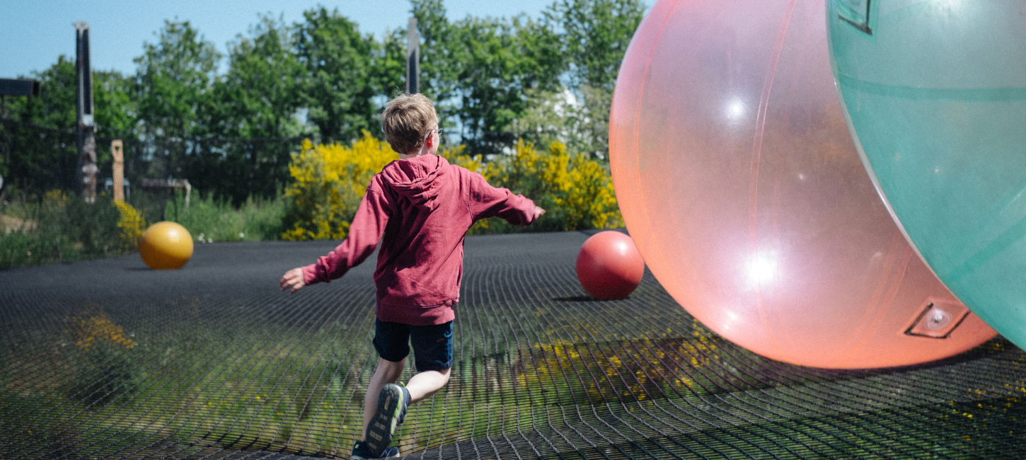 Junge springt im WOW PARK auf großem Trampolin mit großen Bällen