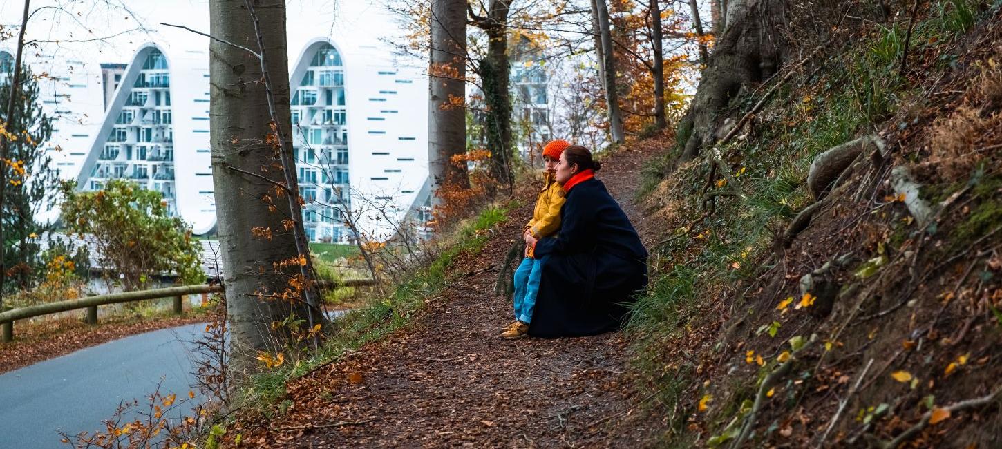 Mutter und Kind bei einem Spaziergang im Nørreskoven in Vejle im Herbst mit Blick auf Bølgen und die Uferpromenade