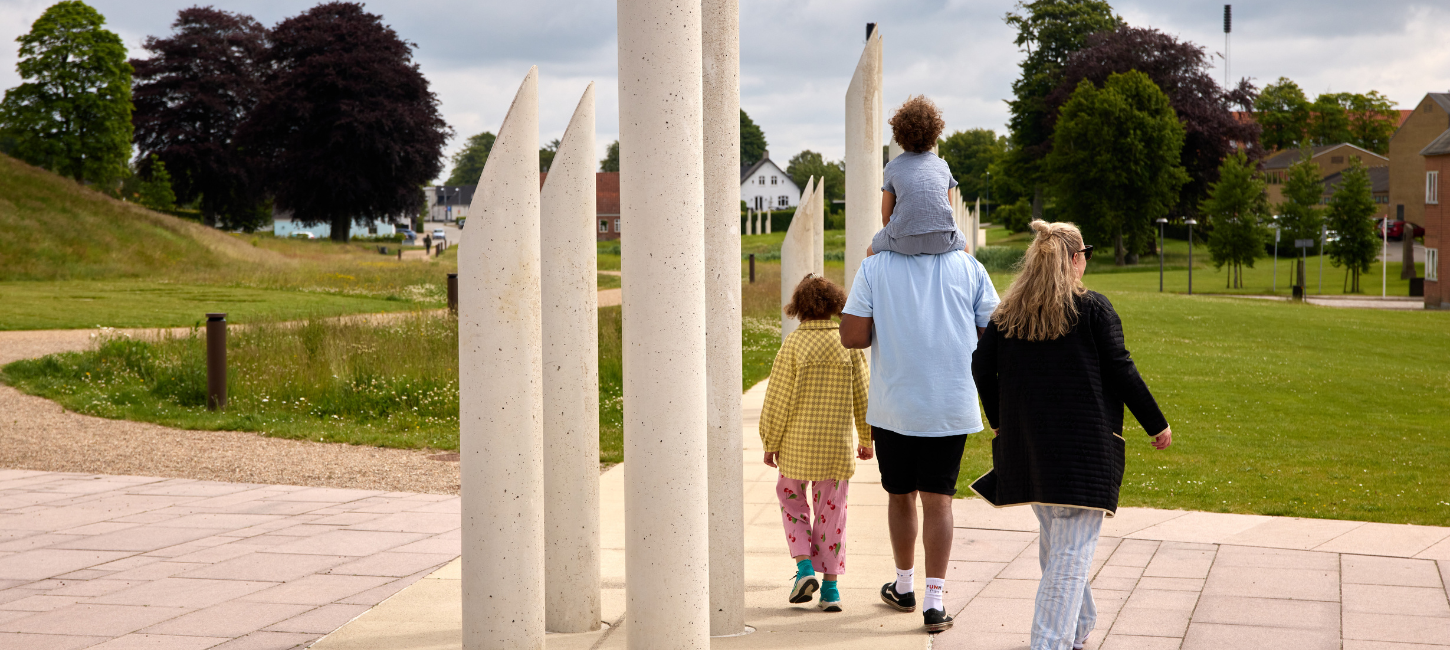 Eine Familie spaziert im Monumentbereich in Jelling bei den Palisaden