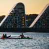 Menschen in Kajaks auf dem Vejle-Fjord mit Bølgen (der Welle) im Hintergrund