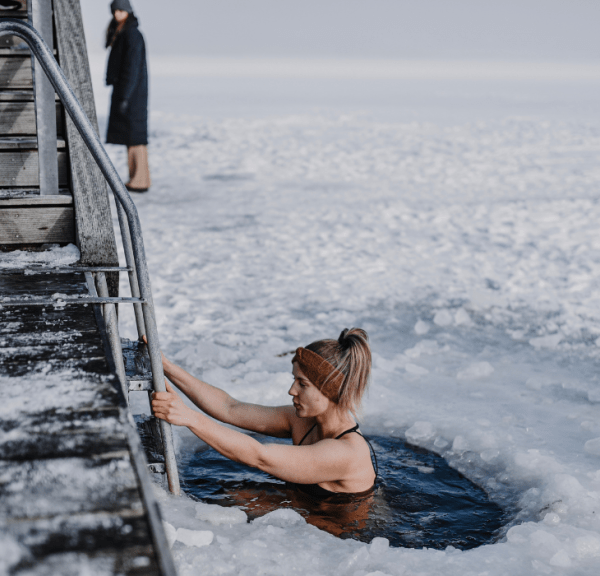 Frau badet im Winter am Fjord mit Eis auf dem Fjord